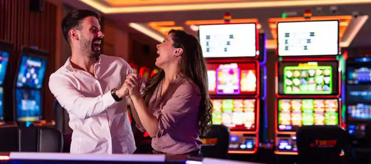 celebrating couple standing amidst casino slot machines
