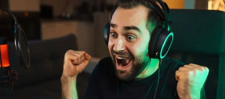man celebrating a win as he looks at laptop screen playing at Slotocash